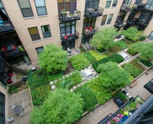Photo looking down into the lush green interior garden courtyard at No. Ten Lofts in the Chicago West Loop neighborhood. You can see yellow brick building.