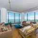 Interior of a luxury Chicago condo showing an open concept living room and kitchen with floor-to-ceiling windows overlooking the downtown city skyline.