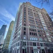 Photo of a classic brick Chicago co-op building against a blue sky. Condo vs. Co-op in Chicago, Buying a Chicago co-op, pros and cons of co-op ownership.