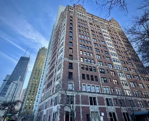 Photo of a classic brick Chicago co-op building against a blue sky. Condo vs. Co-op in Chicago, Buying a Chicago co-op, pros and cons of co-op ownership.